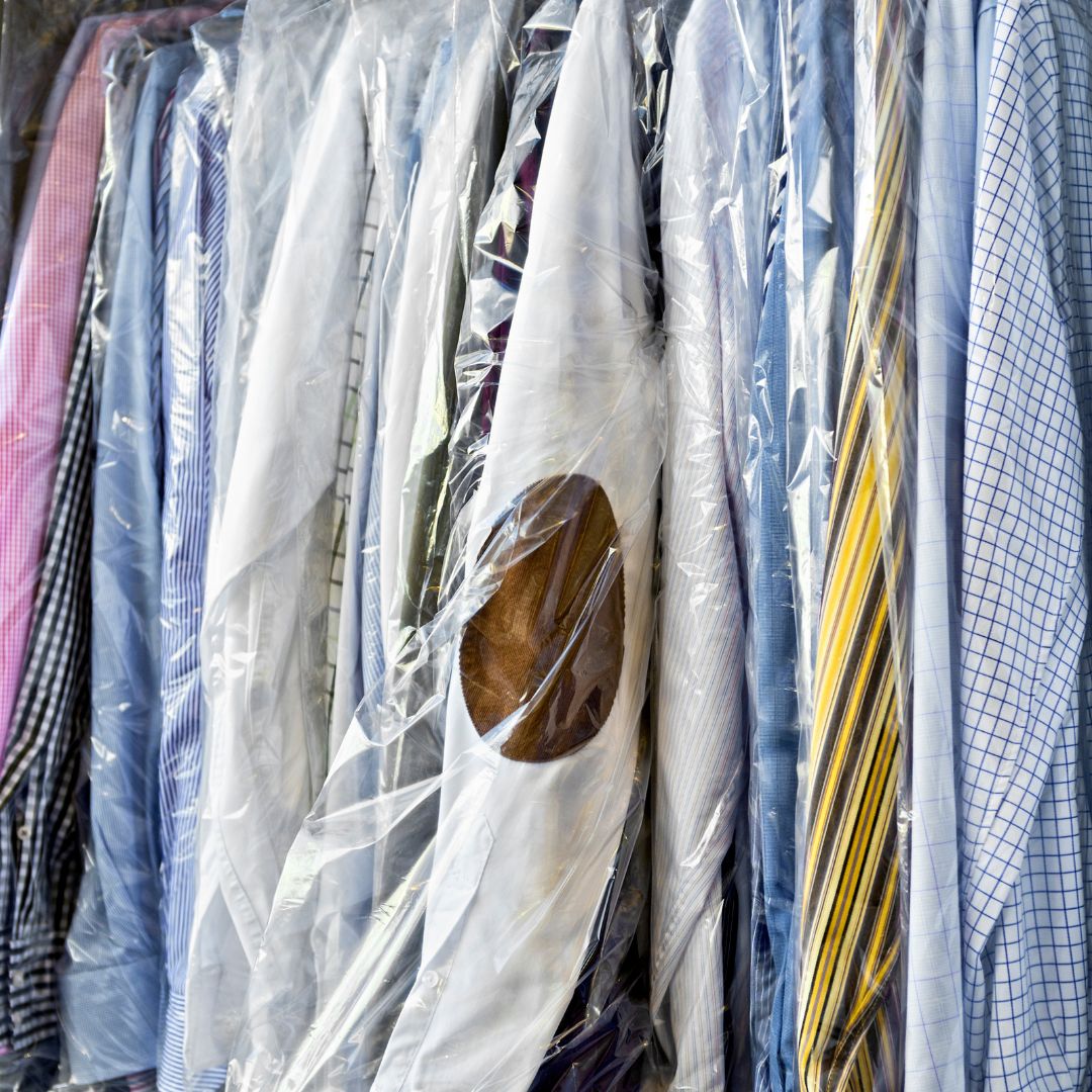 Camisas de tintorería limpias y planchadas colgadas con fundas protectoras