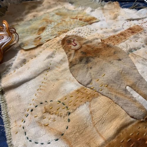 Detalle de costura y bordado artesanal sobre tela antigua